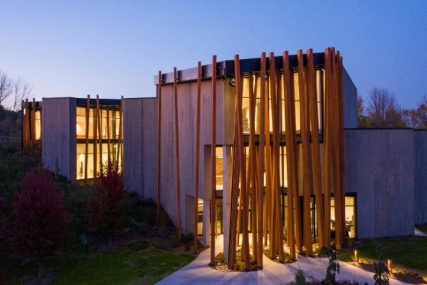 Photo of a concrete building with two dozen three-story wooden beams on the front of floor-to-ceiling windows