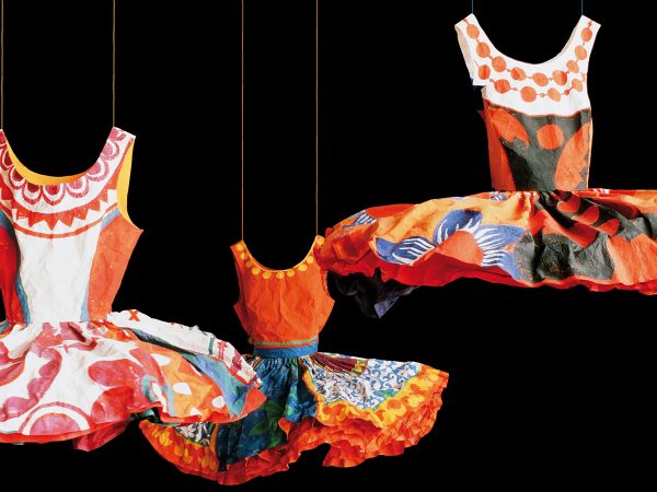 Photo of three colorful paper ballet tutus in the colors of red, white, blue and black with some yellow and covered in various designs