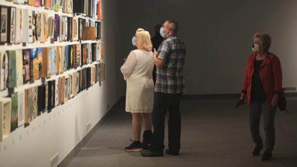 Interior image of the Foot in the Door galleries with multiple visitors looking at paintings on the wall