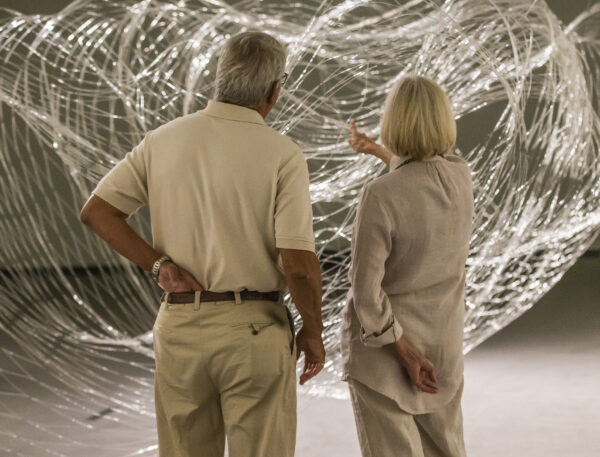 Man and woman standing in front of a large-scale glass sculpture